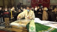 Sveštenik SPC asepsolom briše staklo posle svakog vernika koji celiva odar patrijarha Irineja